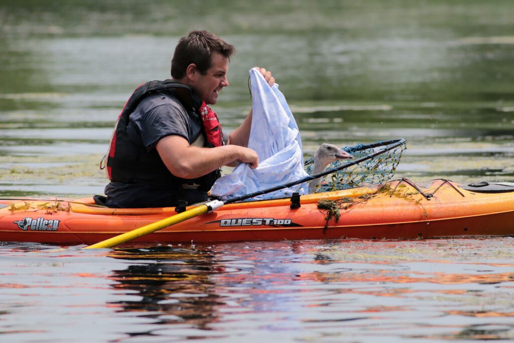 man in kayak with net and plastic bag