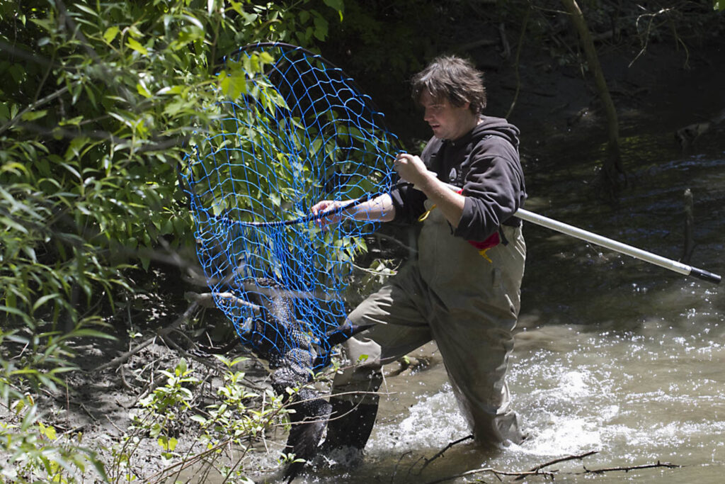 man in waders with net 